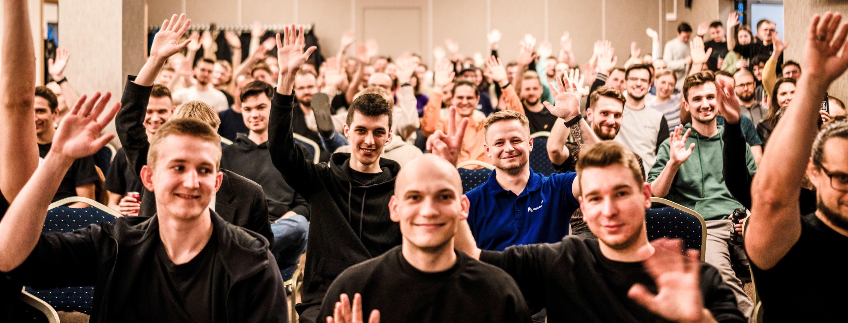 Group in a conference room, smiling, raising hands, peace signs.