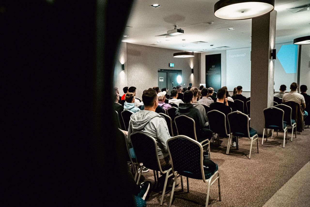 Audience in rows, attentively facing the front where a presentation is shown.