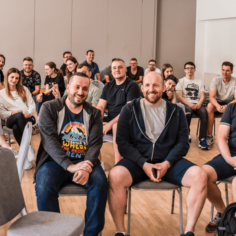 Smiling group in a conference room, with two men in the front row