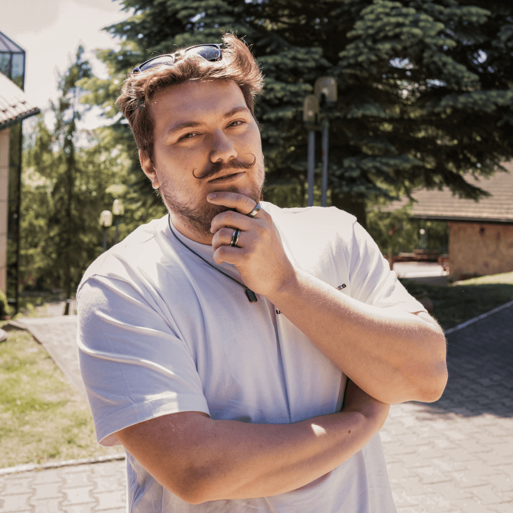 Man with sunglasses on his head, standing outside with a thoughtful expression, hand on chin