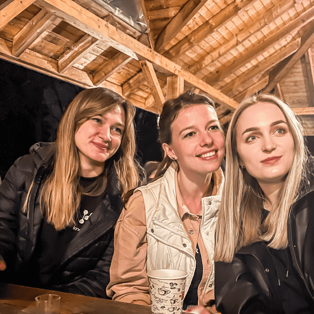Smiling women sitting under a wooden pavilion at night